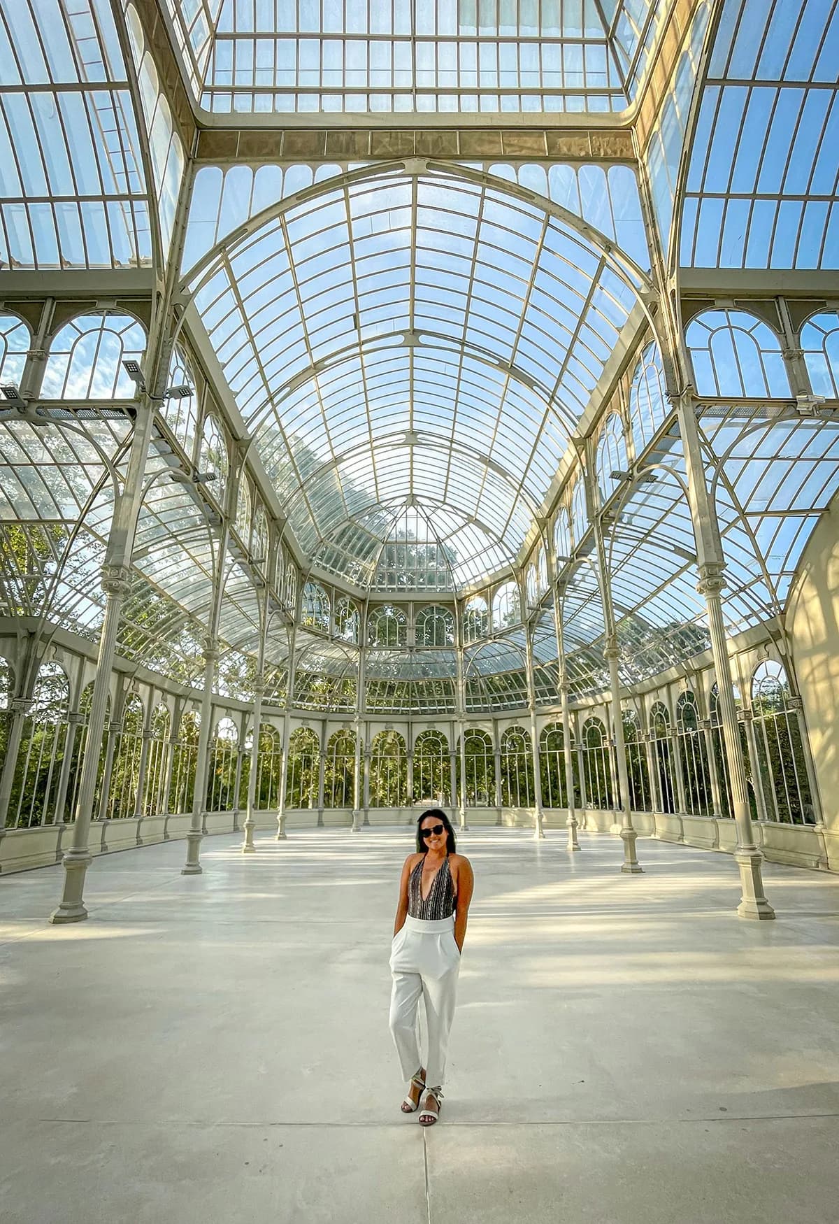 Étudiante dans le Palais de Cristal pendant des cours de langue à Madrid, entourée de verrières et de lumière naturelle.